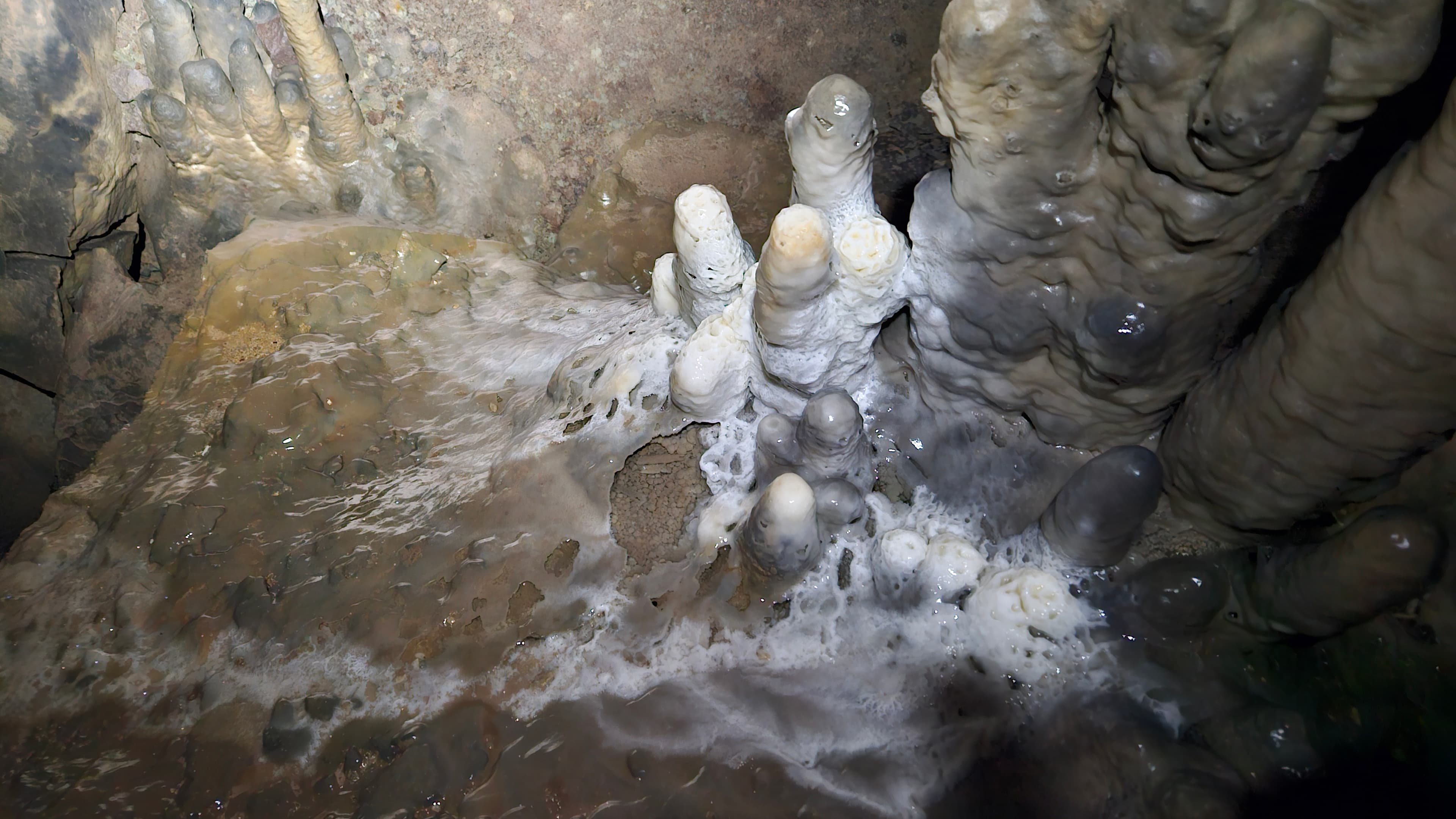 Cavers moving through a spacious cave corridor