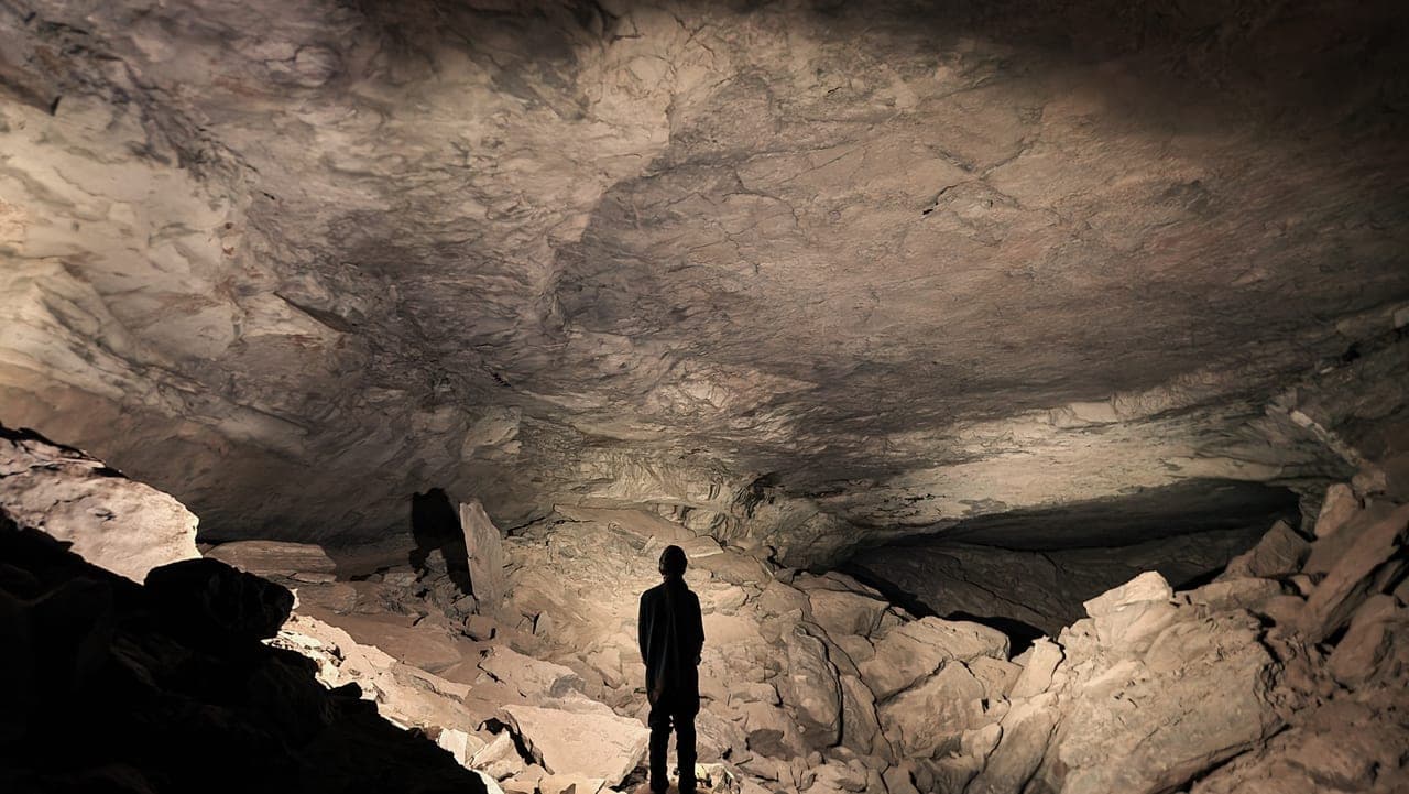 Silhouette of a caver in a large boulder-filled room